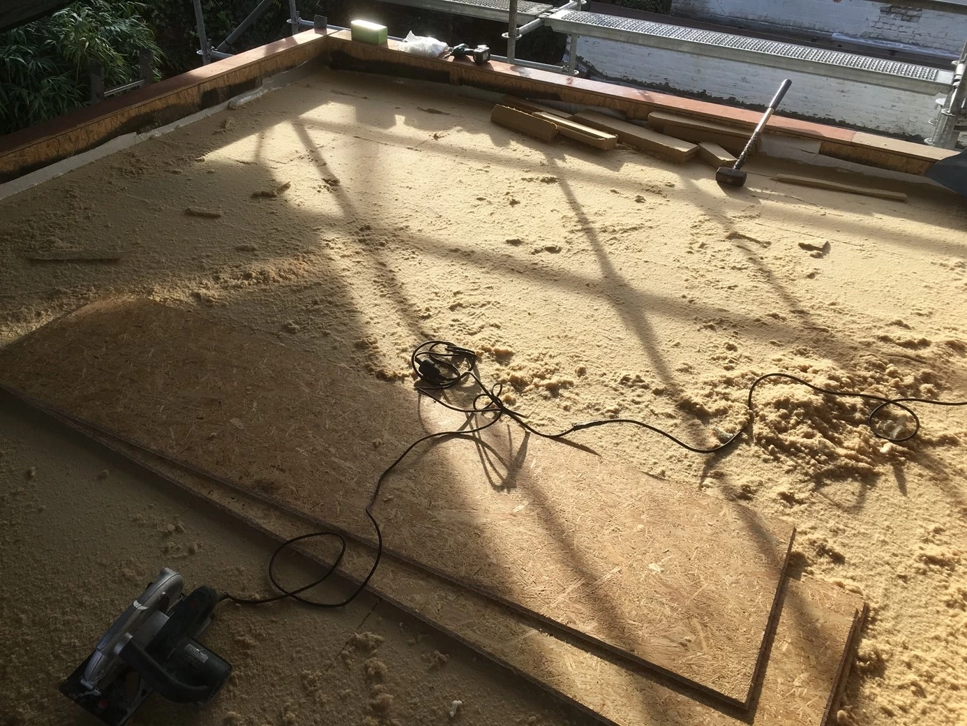 Plaatsen van houtwolplaten (= ecologische isolatie) op de dakconstructie van een aanbouw in houtskelet te Gentbrugge.